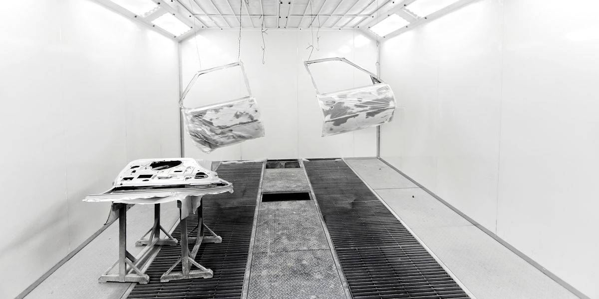 interior of a paint room with bright white walls and ceiling and car doors ready to be painted