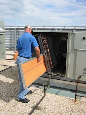 worker replacing a orange air filter in an outside HVAC unit